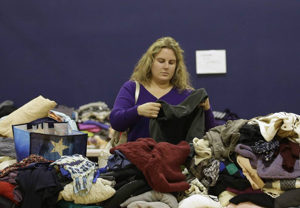 Jenna Latrache looks through clothes at a donation center for victims of the recent wildfires, Tuesday, Oct. 17, 2017, in Santa Rosa, Calif. Latrache lost her Coffey Park home when she and her family had to evacuate a week ago as a massive wildfire swept through the area. (AP Photo/Rich Pedroncelli)