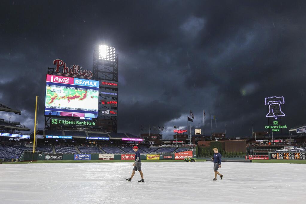 Fanavision monitor showing the movement of a local storm before the downpour as Philadelphia Phillies grounds crew members walk across the tarp before a baseball game with the St. Louis Cardinals' at Citizens Bank Park in Philadelphia, Wednesday, May 29, 2019. Pennsylvania faces a third day of severe weather while people clean up from storms that downed trees, power lines and caused flooding. Thursday's forecast calls for storms that could pack damaging wind and hail. (Steven M. Falk/The Philadelphia Inquirer via AP)