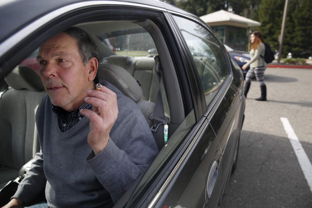 Gary Labriola, of Petaluma, smokes a cigarette in his car while he waits for his wife on the Sonoma State University campus in Rohnert Park , California on Monday, February 2, 2015. (BETH SCHLANKER/ The Press Democrat)
