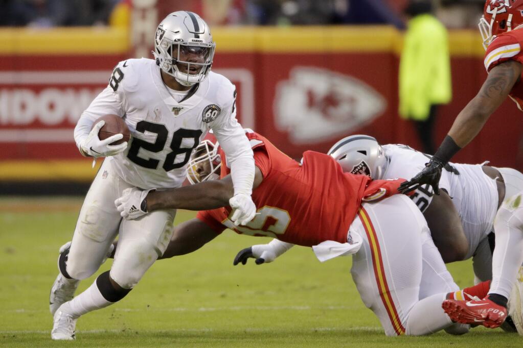Oakland Raiders running back Josh Jacobs tries to break a tackle by Kansas City Chiefs defensive tackle Chris Jones during the first half in Kansas City, Mo., Sunday, Dec. 1, 2019. (AP Photo/Charlie Riedel)