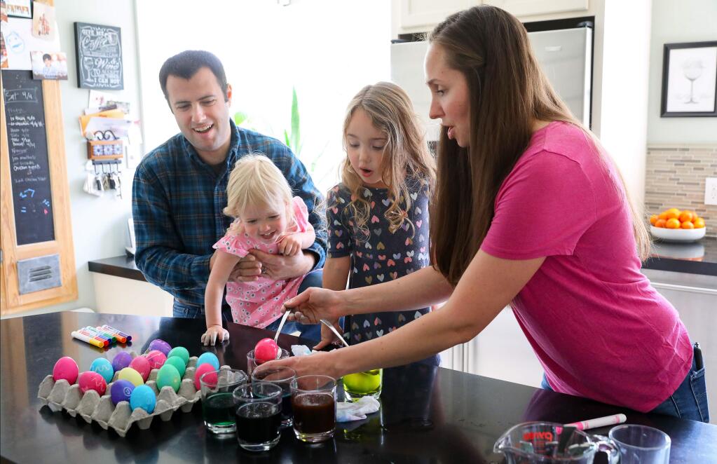 Ben and Jillian Bryant color Easter eggs with their daughters Macie, 1, and Maya, 3, at their home in Santa Rosa on Friday, April 10, 2020. (Christopher Chung/ The Press Democrat)