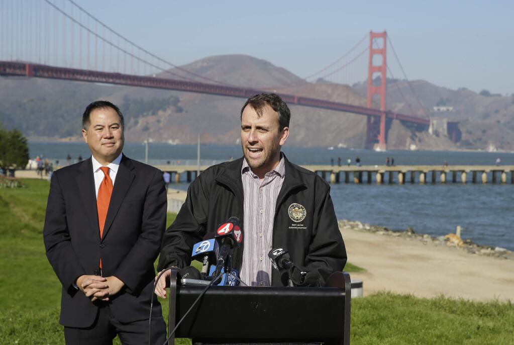 State assembly members Phil Ting, left, and Marc Levine, at podium, speak out against sidewalk tolls with the Golden Gate Bridge in the background during a press conference at Crissy Field Tuesday, Nov. 25, 2014, in San Francisco. (AP Photo/Eric Risberg)