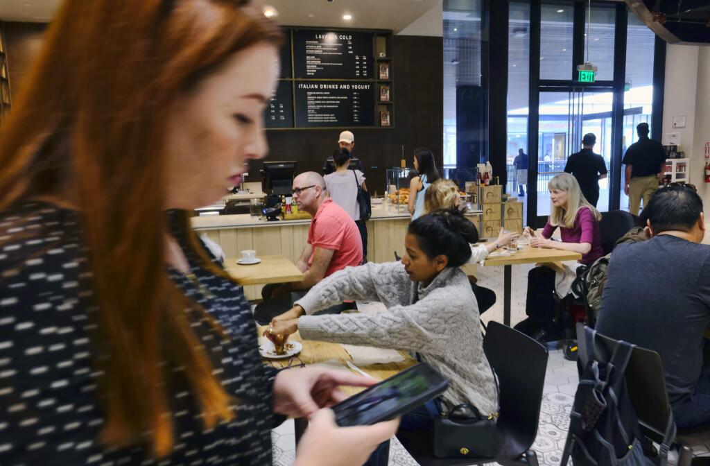 FILE - In this Wednesday, Nov. 22, 2017, file photo, customers sit and have their morning coffee and pastries at the LaVazza Cafe, at Eataly, at the Westfield Century City Mall in the Century City section of Los Angeles. Many mall owners are spending billions to add more upscale restaurants and bars, premium movie theaters, bowling alleys and similar amenities. (AP Photo/Richard Vogel, File)