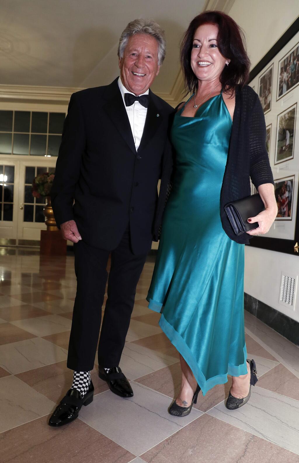 Former racing driver Mario Andretti shows his racing themed socks as he and Barbra Andretti-Curto arrive for a state dinner at the White House for Italian Prime Minister Matteo Renzi, Tuesday, Oct. 18, 2016 in Washington. (AP Photo/Alex Brandon)