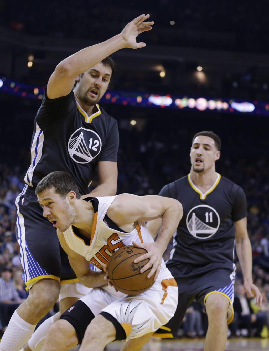 Phoenix Suns' Goran Dragic, bottom, is defended by Golden State Warriors' Andrew Bogut (12) during the first half of an NBA basketball game Saturday, Jan. 31, 2015, in Oakland, Calif. (AP Photo/Marcio Jose Sanchez)
