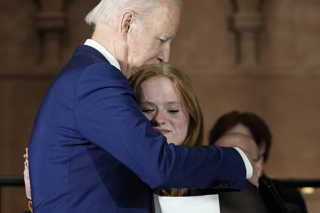 President Joe Biden hugs Sandy Hook survivor Jackie Hegarty, who introduced him, during an event in Washington, Wednesday, Dec. 7, 2022, with survivors and families impacted by gun violence for the 10th Annual National Vigil for All Victims of Gun Violence. (AP Photo/Susan Walsh)