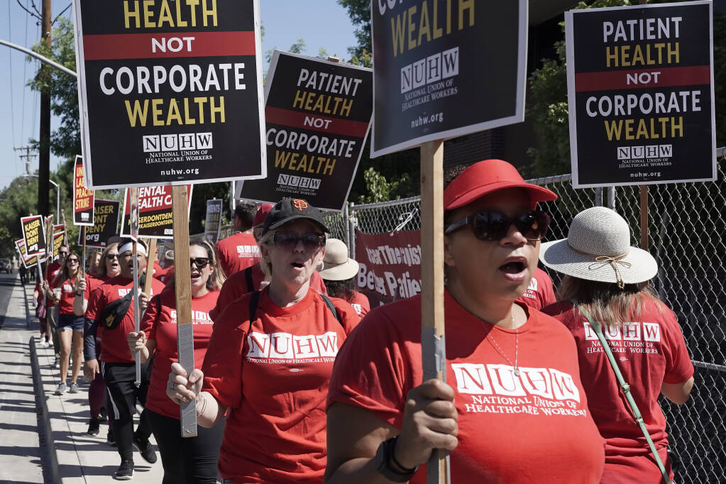 Kaiser Permanente mental health workers and supporters march outside a Kaiser facility in Sacramento, Calif., Monday, Aug. 15, 2022. More than 2,000 Kaiser Permanente psychologists, therapists and other mental health workers in Northern California started an open-ended strike Monday over high workloads and excessive wait times.(AP Photo/Rich Pedroncelli)