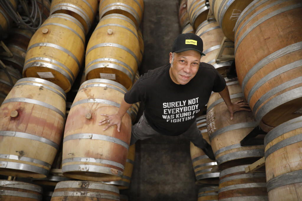 Dan Glover, winemaker and owner of L'Objet Wines, climbs atop barrels of his wine stored at Optima Winery in Healdsburg, Calif., Tuesday, Jan. 31, 2023. (Beth Schlanker/The Press Democrat)