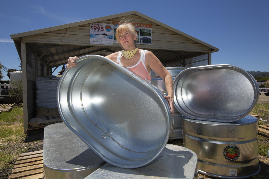 Brocco’s assistant manager Jan Mills with some of the galvanized stock tanks that have become popular for use as gardening boxes. (Photo by Robbi Pengelly/Index-Tribune)