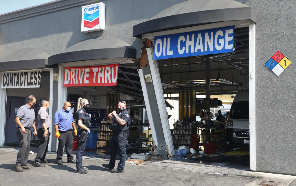 Rohnert Park Police and Chevron Oil Stop employees gather near the damage caused by a vehicle that ran into the building in Rohnert Park on Monday, September 21, 2020.  (Christopher Chung/ The Press Democrat)