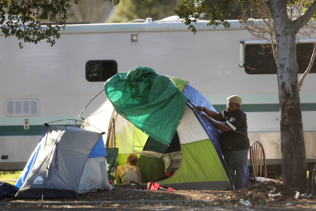 A man named Will makes adjustments to a tent at the homeless encampment on Industrial Drive in Santa Rosa, Calif., on Monday, Jan. 18, 2021. (Beth Schlanker / The Press Democrat)