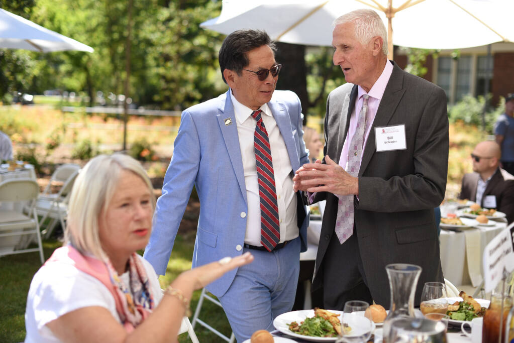 Dr. Frank Chong, center, superintendent and president of Santa Rosa Junior College, chats with guest Bill Schrader before Chong’s address to the community on the campus lawn in Santa Rosa, Calif. on Monday June 6, 2022. (Erik Castro / For The Press Democrat)