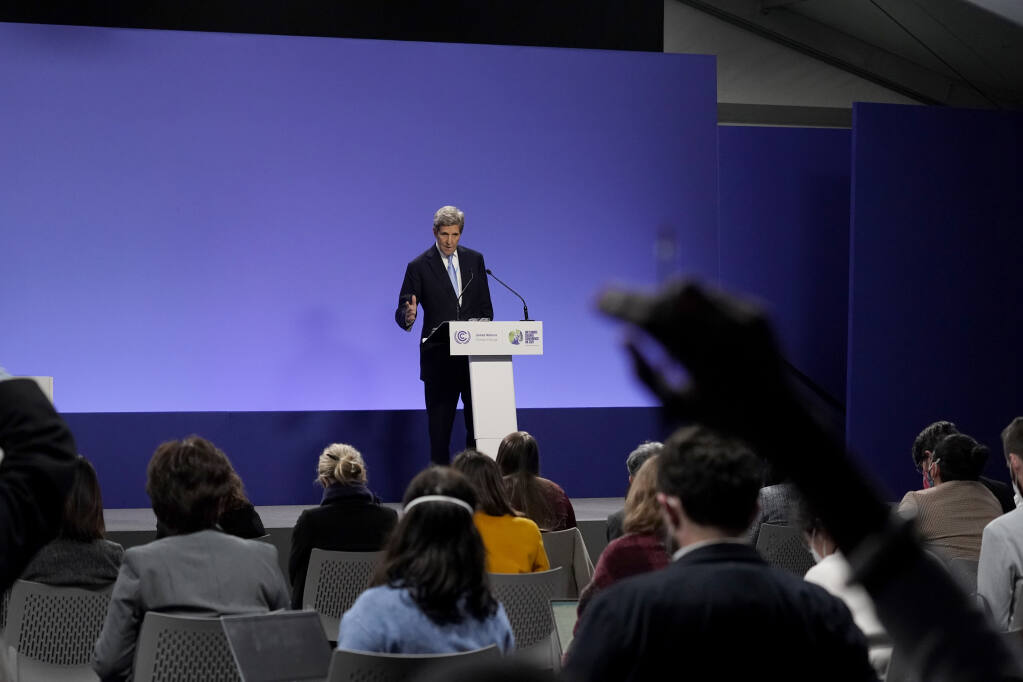 An audience member puts their hand up to try to ask a question as John Kerry, United States Special Presidential Envoy for Climate, speaks immediately after a press conference given by China's Special Envoy for Climate Change Xie Zhenhua at the COP26 U.N. Climate Summit, in Glasgow, Scotland, Wednesday, Nov. 10, 2021. The U.N. climate summit in Glasgow has entered its second week as leaders from around the world, are gathering in Scotland's biggest city, to lay out their vision for addressing the common challenge of global warming. (AP Photo/Alberto Pezzali)