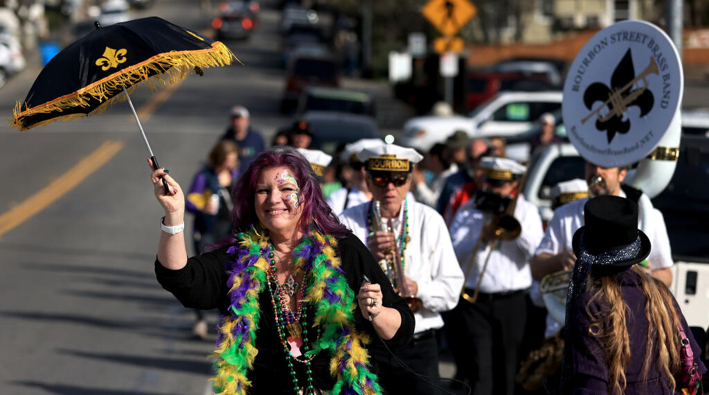 Amber Gray, with the Forestville Chamber of Commerce, leads a musical procession of Mardi Gras revelers along Highway 116 in Forestville, Saturday, Feb. 18, 2023, as part of a celebration at the Forestville Downtown Oaks Park. (Kent Porter / The Press Democrat) 2023