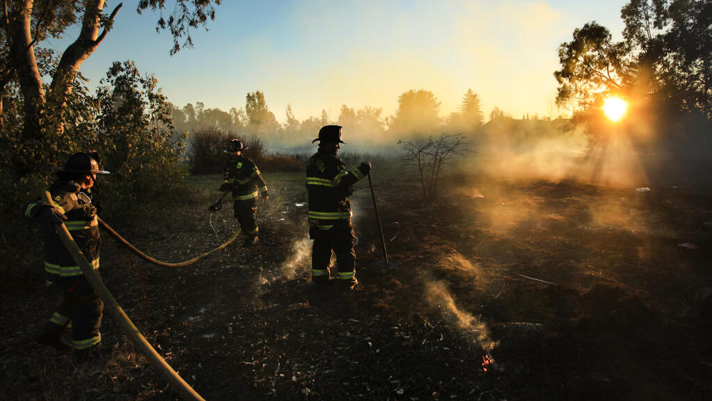Santa Rosa firefighters mop at the scene of a 1/4-acre brush fire pushed by strong winds near a homeless encampment in a grove of eucalyptus trees off Piner Road, Monday, Jan. 18, 2021 in Santa Rosa.  (Kent Porter / The Press Democrat) 2021