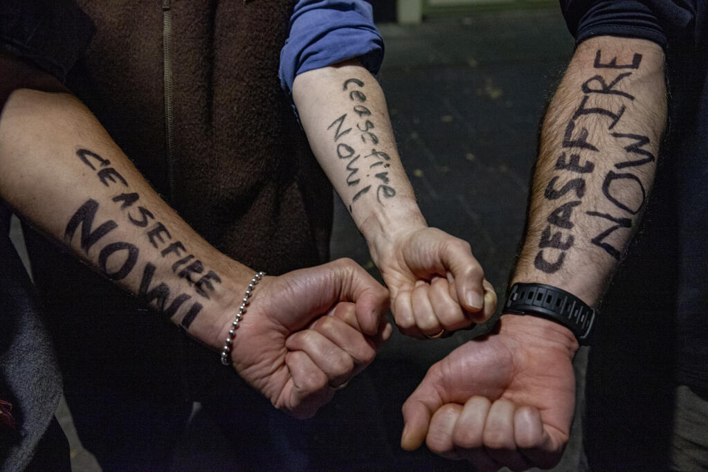 Activists write “Ceasefire Now” on their arms in calling for a ceasefire in Gaza. Photographed on Monday, October 30, 2023. (CRISSY PASCUAL/ARGUS-COURIER STAFF)