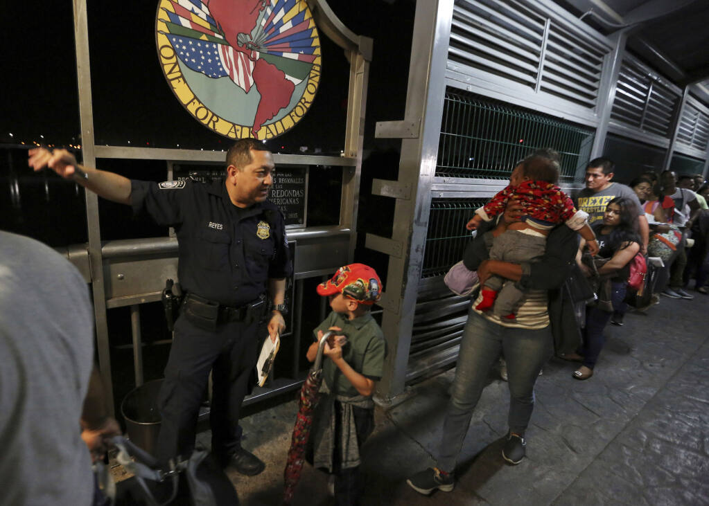 FILE - In this Sept. 17, 2019, file photo, a U.S. Customs and Border Protection officer gives instructions to migrants who are on their way to apply for asylum in the United States, on International Bridge 1 as they depart Nuevo Laredo, Mexico. A federal judge on Monday, Aug. 31, 2020, blocked U.S. Customs and Border Protection employees from conducting the initial screening for people seeking asylum, dealing a setback to one of the Trump administration's efforts to rein in asylum. (AP Photo/Fernando Llano, File)