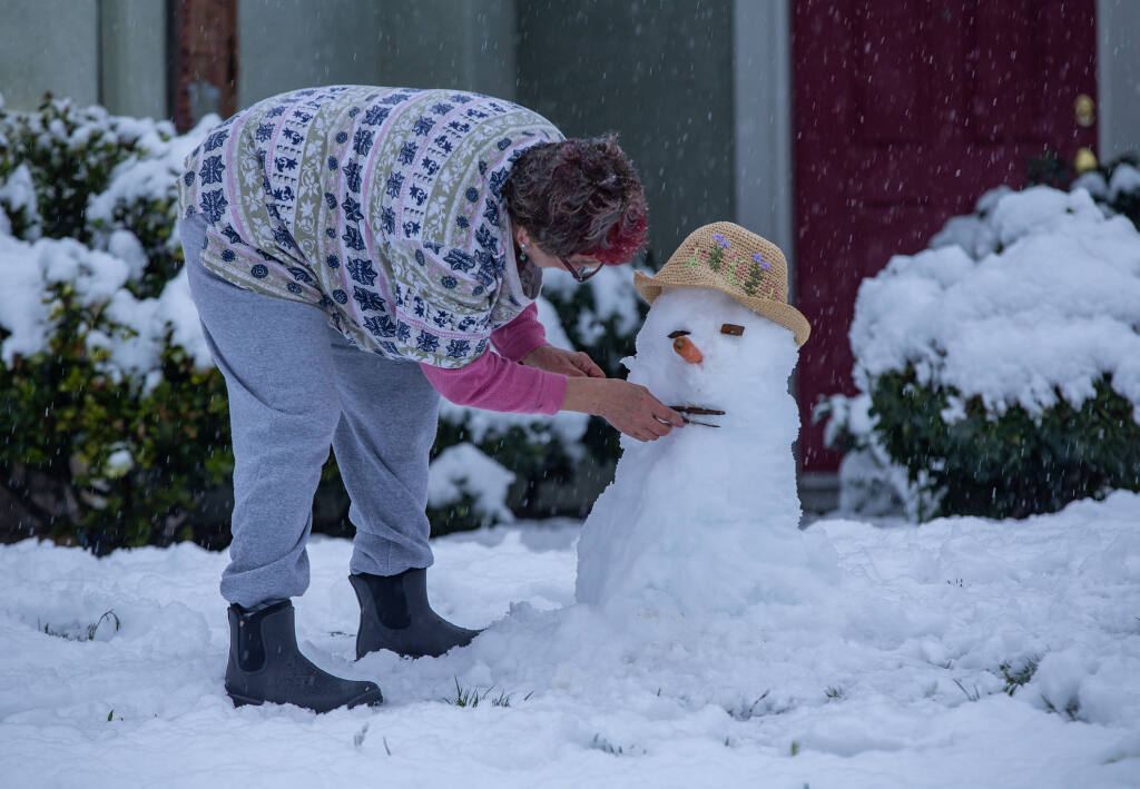 Dee Simpson of Cloverdale builds a snowman in her front yard as residents woke to a snow covered landscape in the Clover Springs subdivision after a rare late February storm brought an inch of snow to the area Feb. 24, 2023. (Chad Surmick / The Press Democrat)