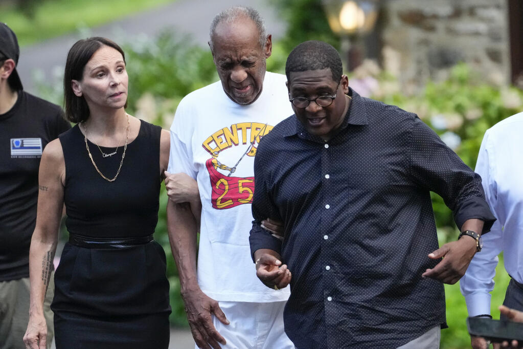 Bill Cosby, center, and spokesperson Andrew Wyatt, right, approach members of the media gathered outside Cosby's home in Elkins Park, Pa., Wednesday, June 30, 2021, after Pennsylvania's highest court overturned his sex assault conviction. (AP Photo/Matt Slocum)