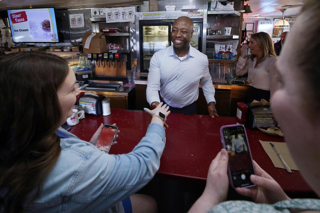 FILE - Sen. Tim Scott, R-S.C., shakes hands with diners at the breakfast counter during a visit to the Red Arrow Diner, Thursday, April 13, 2023, in Manchester, N.H. Scott has filed paperwork to enter the 2024 Republican presidential race. He'll be testing whether a more optimistic vision of America’s future can resonate with GOP voters who have elevated partisan brawlers in recent years.(AP Photo/Charles Krupa, File)