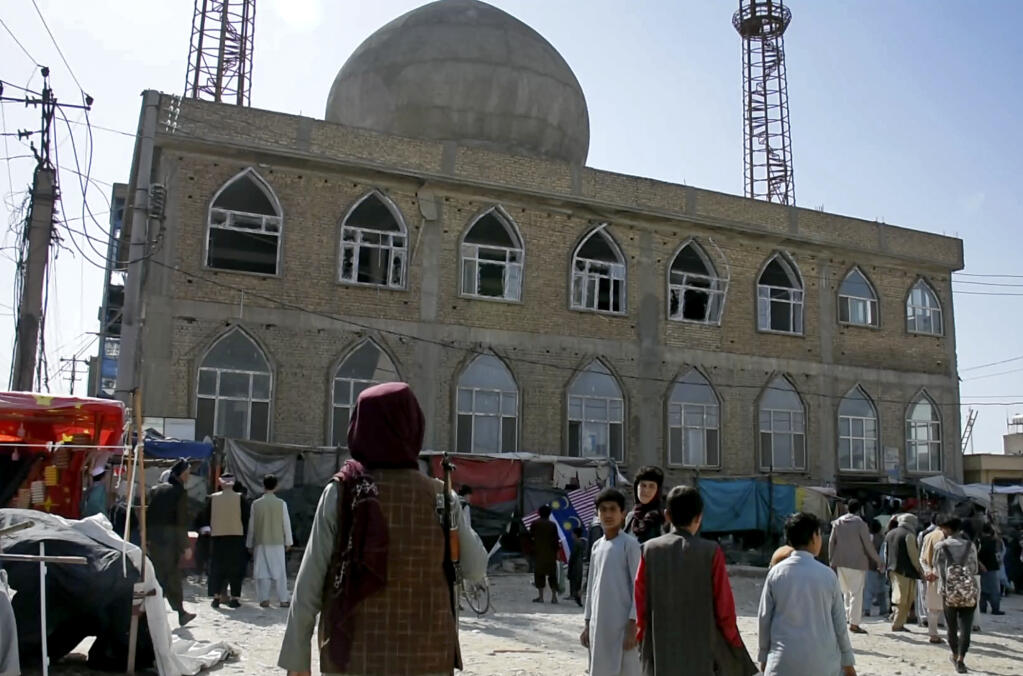 FILE - This frame grab image from video, shows a Taliban fighter standing guard outside the site of a bomb explosion inside a mosque, in Mazar-e-Sharif province, Afghanistan, Thursday, April 21, 2022. A deadly Islamic State affiliate on Friday, April 22, 2022, claimed a series of bombings  a day earlier that targeted Afghanistan’s minority Shiite Muslims, while Pakistan issued a warning of IS threats in its eastern Punjab province. (AP Photo, File)