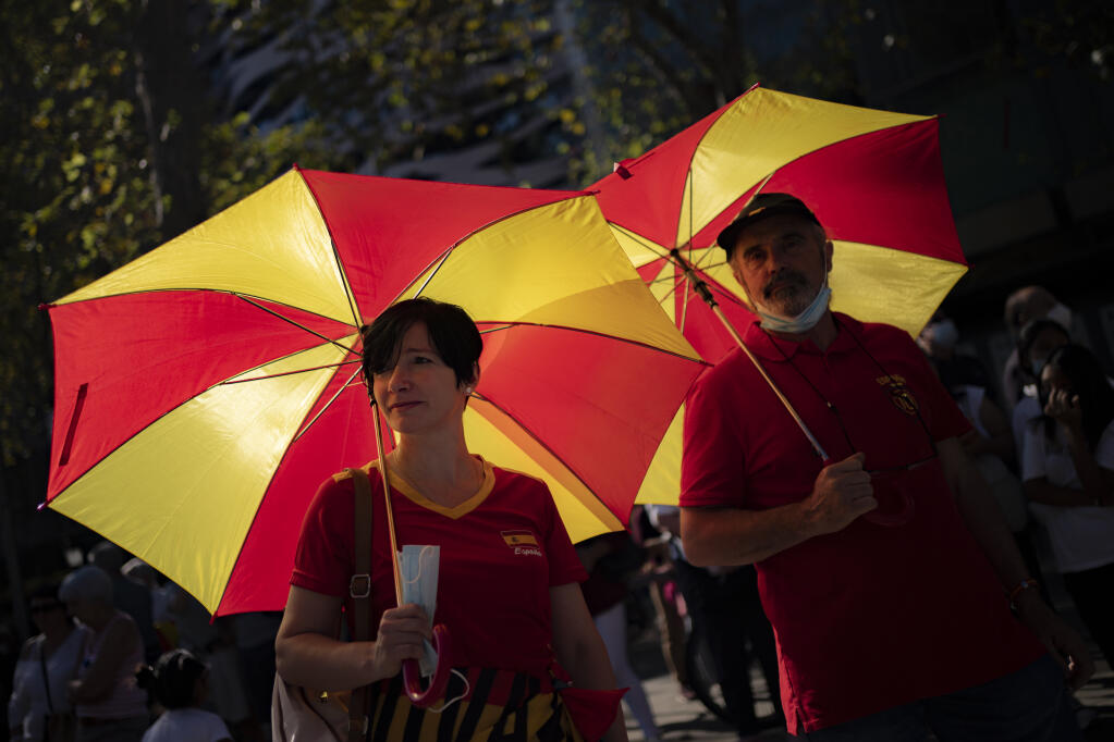 Two demonstrators hold umbrellas decorated with the colours of the Spanish flag during a celebration for Spain's National Day in Barcelona, Spain, Tuesday, Oct. 12, 2021. Spain commemorates Christopher Columbus' arrival in the New World and also Spain's armed forces day. (AP Photo/Joan Mateu Parra)