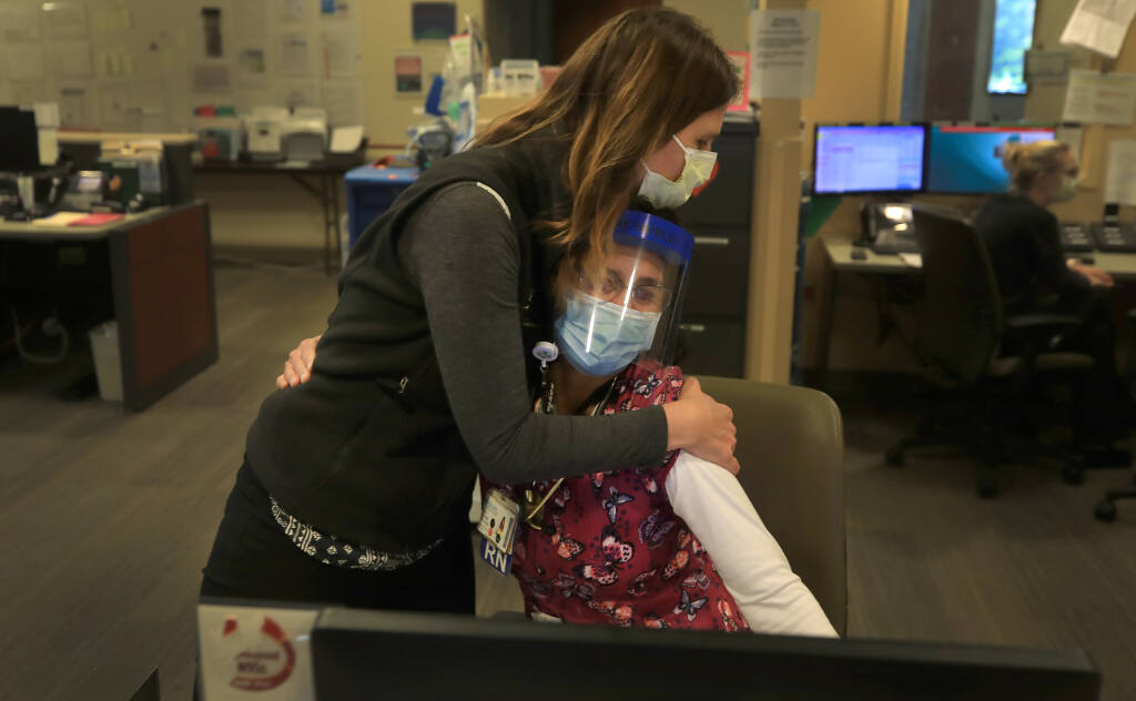 Dr. Veronica Jordan, a family medicine doctor at Sutter Santa Rosa Regional Hospital, left, embraces registered nurse Cora Kendall  as the emotion of talking about caring for patients with COVID-19 for a year, causes Kendall to tear up, Thursday, March 11, 2021. (Kent Porter / The Press Democrat)