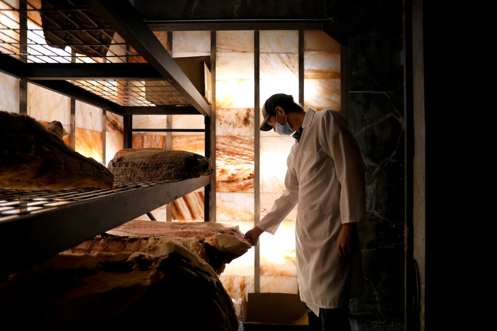 Ryan Taylor co-owner Panizzera Meat Co. goes inside a meat locker lined with salt blocks used for humidity control in Occidental on Tuesday, Aug. 3, 2021. (Beth Schlanker / The Press Democrat)