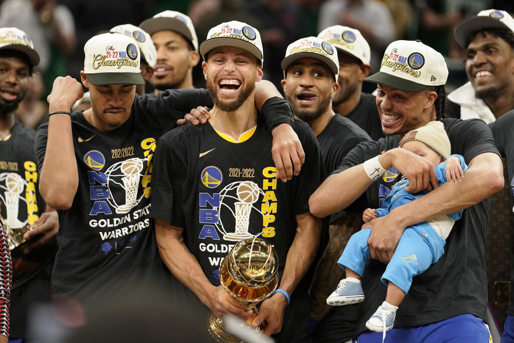 Golden State Warriors guard Stephen Curry, center, celebrates with teammates as he holds the Bill Russell Trophy for Most Valuable Player after the Warriors beat the Boston Celtics in Game 6 to win the NBA Finals, Thursday, June 16, 2022, in Boston. (AP Photo/Steven Senne)
