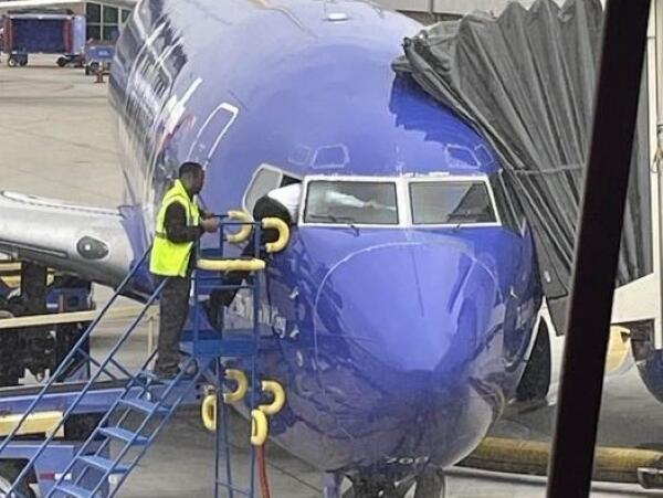 The pilot of a Sacramento-bound plane at a gate in San Diego International Airport climbs through a window after getting locked out on May 24, 2023. (Matt Rexroad / Twitter)