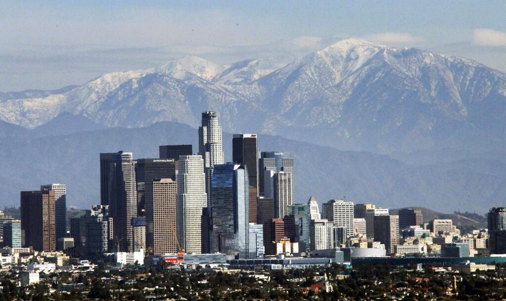 FIE - In this Dec. 31, 2014, file photo, the snow-capped San Gabriel Mountains provide a backdrop to the downtown Los Angeles skyline as seen from Kenneth Hahn State Recreation Area in Baldwin Hills. California greenhouse gas emissions fell below 1990 levels, meeting an early target years ahead of schedule and putting the state well on its way toward reaching long-term goals to fight climate change, officials said Wednesday, July 11, 2018. (AP Photo/Nick Ut, File)
