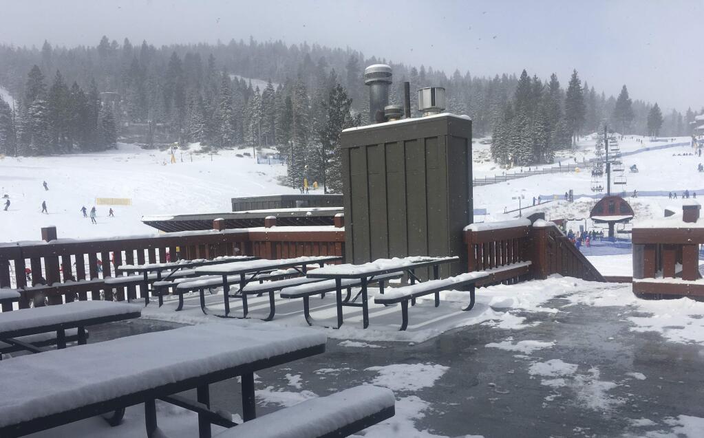 This Thursday, Feb. 22, 2018 photo shows a scene from Northstar Ski Resort in Truckee, Calif. snow covered benches with people skiing on the hills in the background. Cold and blustery weather blew through California on Friday, scattering snow showers in the mountains and making travel on icy roads potentially hazardous but still failing to deliver winter's normal measure of precipitation. (AP Photo/Daisy Nguyen)