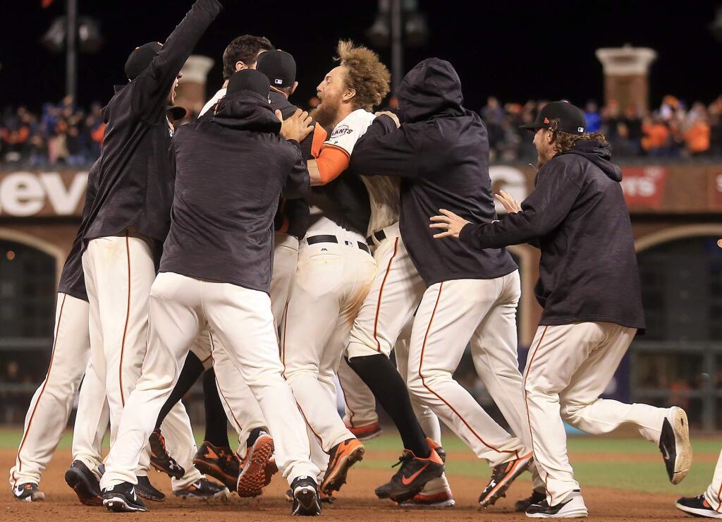 Joe Panik's mobbed by his teammates after he clubbed a walk off single scoring Brandon Crawford to give the Giants a 6-5 victory in 13 innings during game 3 of the NLDS, Monday Oct. 10, 2016 at AT&T Park in San Francisco. (Kent Porter / The Press Democrat) 2016