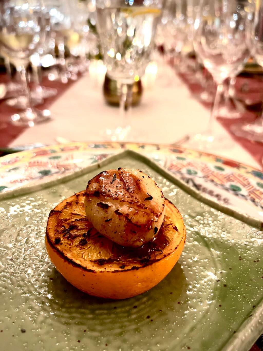 The table setting shines in the background of one dish - the seared scallop atop a grilled orange half - served during a recent reunion dinner as part of a Lunar New Year’s Celebration. (COURTESY OF LANCE LEW)