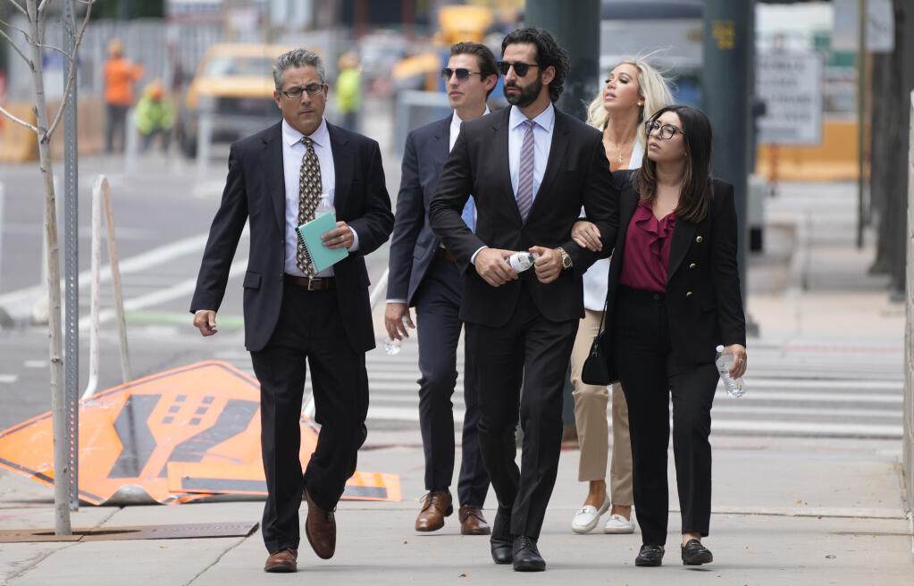 A defense investigator, left, for Pittsburgh dentist Lawrence "Larry" Rudolph heads into federal court with the dentist's children, front center and back right, for the afternoon session of the trial, Wednesday, July 13, 2022, in Denver. (AP Photo/David Zalubowski)