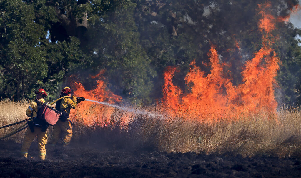 Firefighters battle a brush fire near the Sebastopol city limit, Tuesday, July 20, 2021, south of Highway 12, in the Laguna de Santa Rosa. (Kent Porter / The Press Democrat)