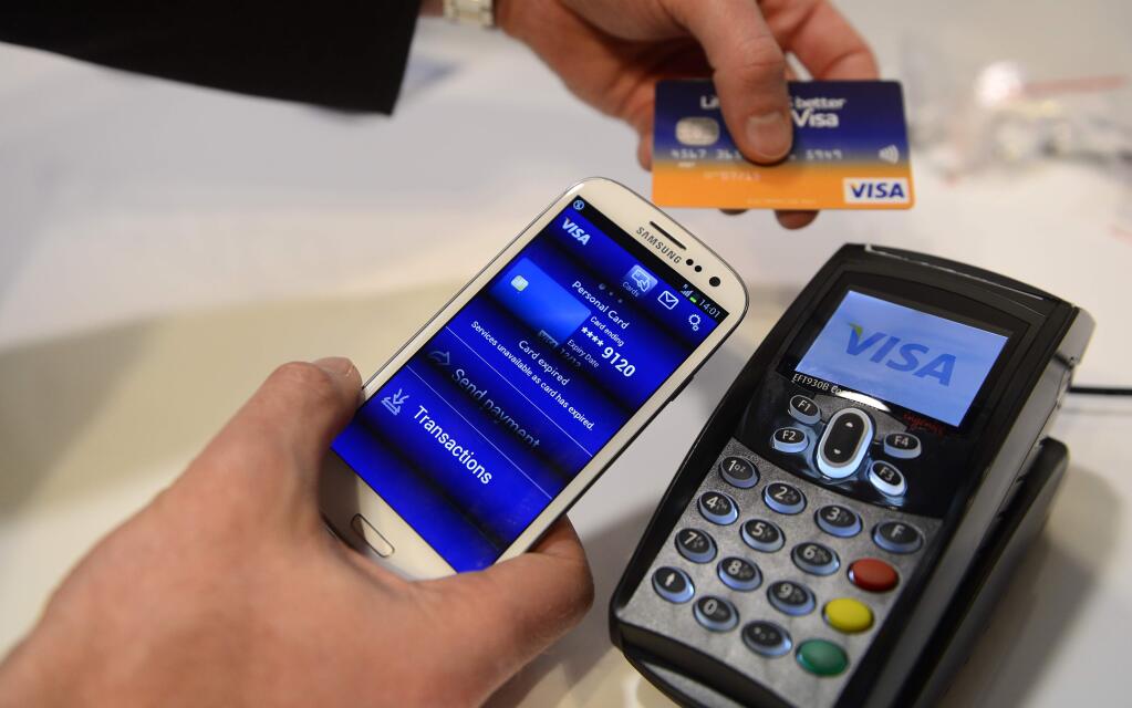 FILE - In this Wednesday, Feb. 27, 2013, file photo, a man uses the NFC payment Visa system at the Mobile World Congress, the world's largest mobile phone trade show, in Barcelona, Spain. Visa is looking to push more small businesses into updating their digital payment technology, offering up to $500,000 to 50 U.S.-based small business owners that are committed to going cashless. (AP Photo/Manu Fernandez, File)