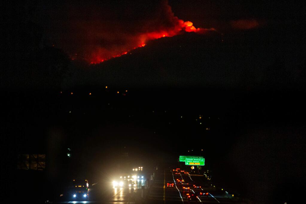 Flames and smoke from the Kincade Fire outline the hills above Highway 101 in Santa Rosa, California, on Wednesday, October 30, 2019. (Alvin Jornada / The Press Democrat)