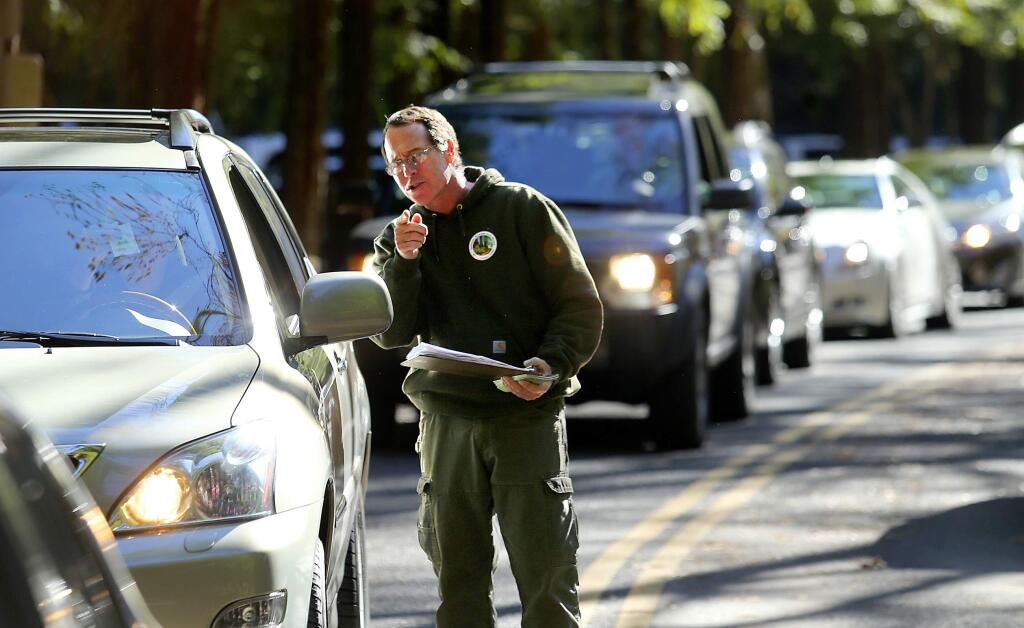 Craig Wilkinson, with the Stewards of the Coast and Redwoods, collects free passes offered by the group from a line of cars at Armstrong Woods State Park on the day after Thanksgiving. (JOHN BURGESS / The Press Democrat)
