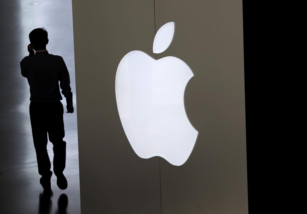 In this Sept. 5, 2014, file photo, a Chinese man talking on his phone walks into an Apple store in Beijing. (AP Photo/Andy Wong, File)