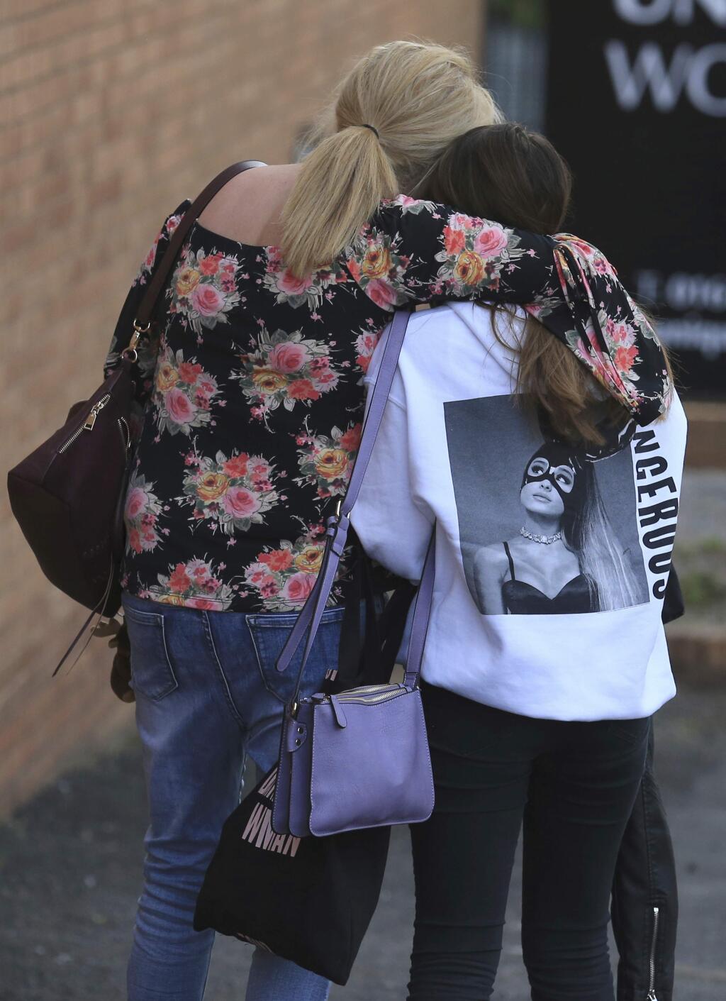 A fan is comforted as she leaves the Park Inn hotel in central Manchester, England Tuesday May 23 2017. Over a dozen of people were killed in an explosion following a Ariana Grande concert at the Manchester Arena late Monday evening. (AP Photo/Rui Vieira)