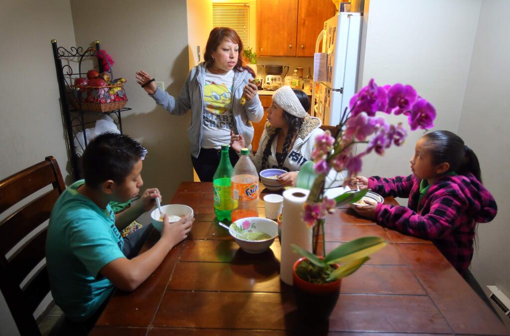 Karla Orozco, standing, talks with her children, Jobani Sanchez, 12, left, Janet Sanchez, 15, and Jacquline Sanchez, 7, as they eat breakfast in their apartment before heading off to school in Santa Rosa on Friday, January 16, 2015. Code enforcement officers confirmed that the families living in the the ten-unit Hoen Avenue apartment complex have been plagued by rodent and cockroach infestations, dangerous levels of mold, and other substandard conditions.(Christopher Chung/ The Press Democrat)