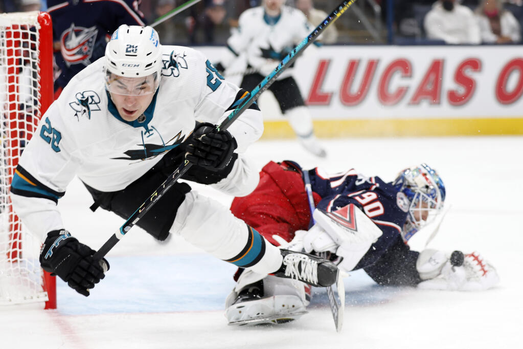 The Columbus Blue Jackets’ Elvis Merzlikins, right, makes a save as the Sharks’ Timo Meier trips during the first period on Sunday, Dec. 5, 2021, in Columbus, Ohio. (Jay LaPrete / ASSOCIATED PRESS)