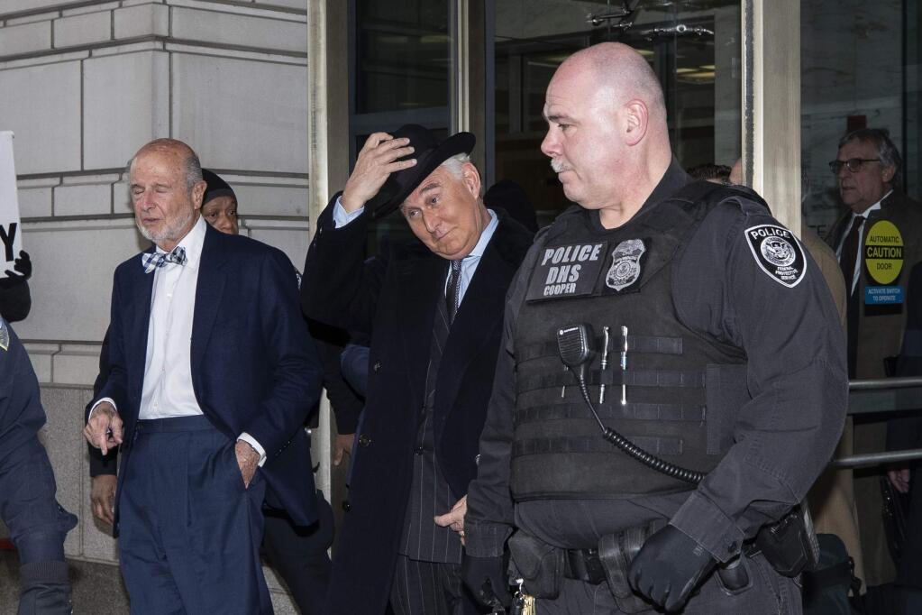 Roger Stone, center, puts his hat on as he departs after his sentencing at federal court in Washington, Thursday, Feb. 20, 2020. President Donald Trump loyalist and ally, Roger Stone was sentenced to over three years in federal prison, following an extraordinary move by Attorney General William Barr to back off his Justice Department's original sentencing recommendation. The sentence came amid President Donald Trump's unrelenting defense of his longtime confidant that led to a mini-revolt inside the Justice Department and allegations the president interfered in the case. (AP Photo/Alex Brandon)