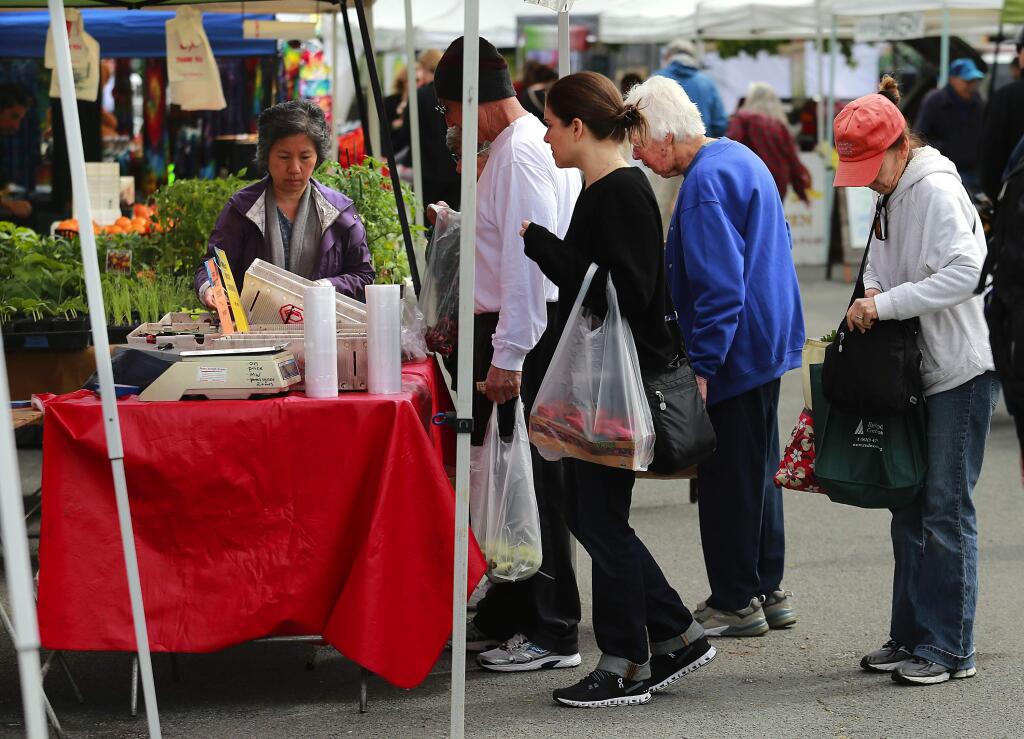 Customers line up for fresh cherries at the Petaluma Eastside farmer's market at Lucchesi Park on Tuesday. (John Burgess/The Press Democrat)