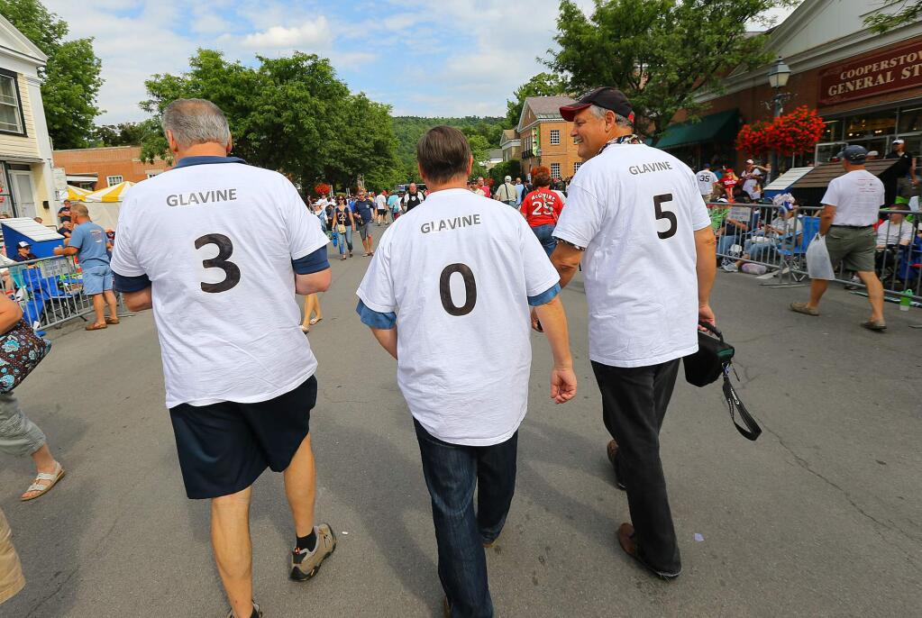 Kent Langworthy, Kevin McIlraith, and Tom Williamson, from left, from Peachtree City, Ga., walk down a street sporting shirts with the numbers 3, 0 and 5 for Tom Glavine's 305 career wins on Saturday, July 26, 2014, in Cooperstown, N.Y. The fronts of their shirts display the number of Greg Maddux's wins. (AP Photo/Atlanta Journal Constitution, Curtis Compton)