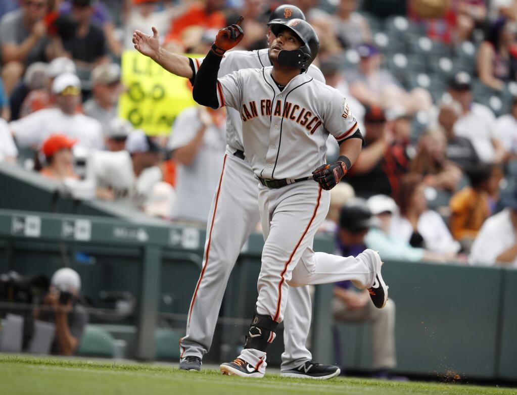 San Francisco Giants' Donovan Solano, front, gestures as he circles the bases after hitting a solo home run off Colorado Rockies starting pitcher Jon Gray in the sixth inning of a baseball game Wednesday, July 17, 2019, in Denver. San Francisco Giants third base coach Ron Wotus, back, looks on. (AP Photo/David Zalubowski)