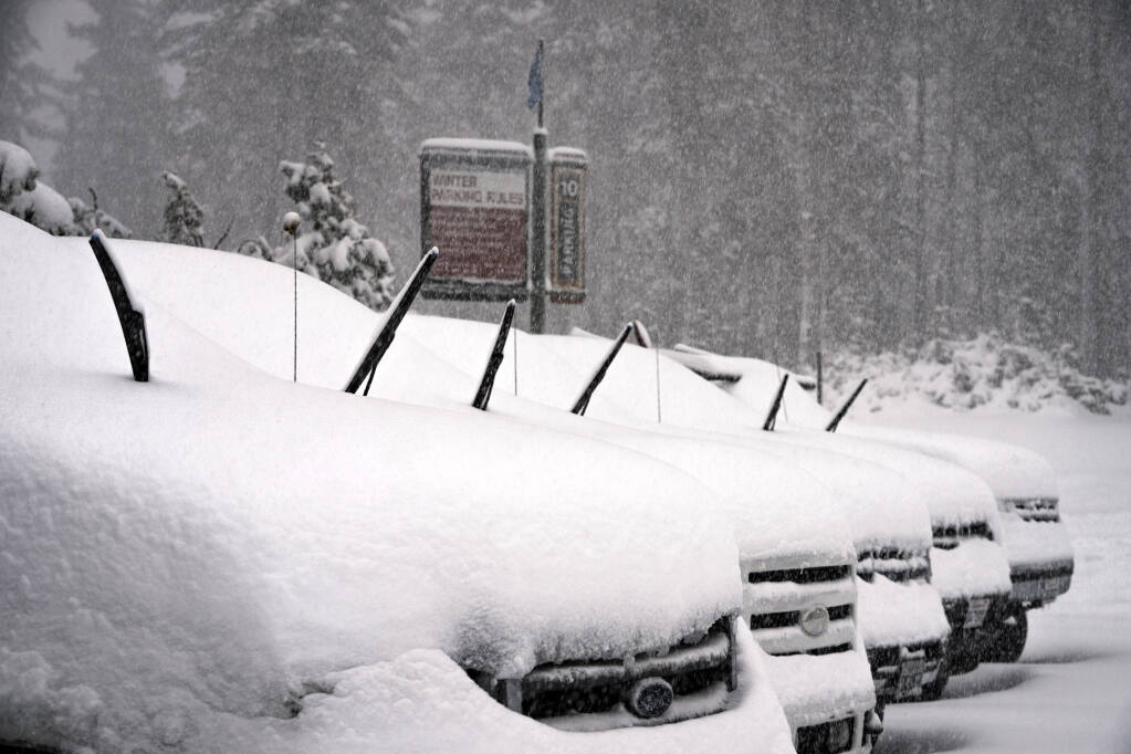 In this photo provided by Mammoth Mountain Ski Area, falling snow collects on cars in a parking lot at Mammoth Mountain, Monday, Oct. 25, 2021, in Mammoth Lakes, Calif.  (Christian Pondella/Mammoth Mountain Ski Area via AP)