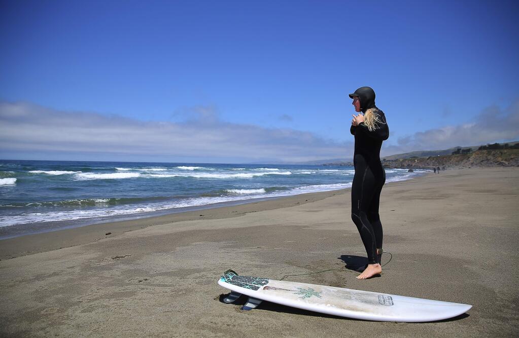 Megan Halavais, of Bodega Bay, fastens her hood before heading out to surf at Salmon Creek Beach, north of Bodega Bay, on Wednesday, May 25, 2016. (Christopher Chung/ The Press Democrat)