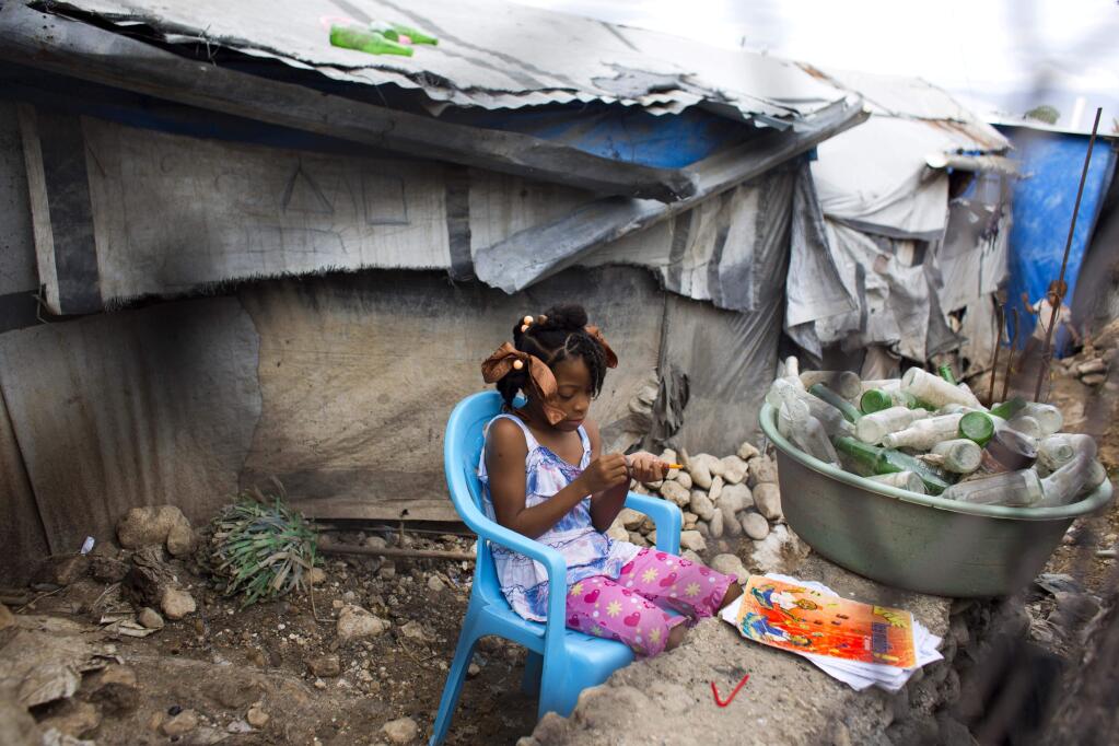 Seven-year-old Ducler Sarah Roudencia sharpens her pencil while she studies her lesson in the Caradeux refugee camp set up nearly eight years ago for people displaced by the 2010 earthquake, in Port-au-Prince, Haiti, Thursday, Jan. 11, 2018. Haitians reacted with outrage Friday to reports that President Donald Trump used a vulgar remark to describe the country on the eve of the anniversary of the 2010 earthquake, one of the deadliest disasters in modern history. (AP Photo/Dieu Nalio Chery)